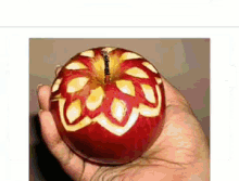 a person is holding a carved apple with a butterfly design