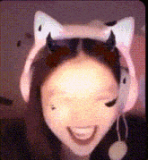 a girl wearing a cat ear headband with horns on it is smiling .