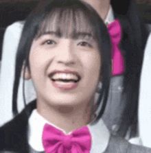 a young girl wearing a pink bow tie is smiling .