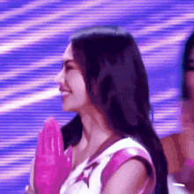 a close up of a woman wearing pink gloves on a stage with a purple background .