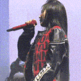 a woman singing into a microphone wearing a jacket with the word rca on it