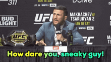 a man sitting at a table with a microphone in front of a ufc sign