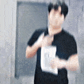 a blurry picture of a man in a black shirt holding a piece of paper in his hand .