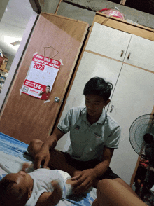 a man is changing a baby 's diaper in front of a poster that says gavin na natini