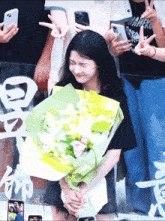 a woman holding a bouquet of flowers with a man wearing a shirt that says waneko on it