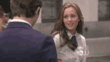 a man and a woman are looking at each other and the man is wearing a suit and tie .