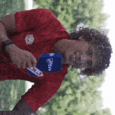 a man in a red shirt is holding a microphone that says n.de f on it