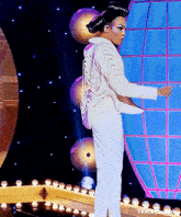 a woman in a white suit is standing on a stage with a globe in the background