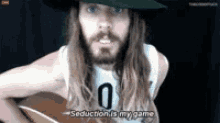 a man with long hair and a beard is playing a guitar and says seduction is my game