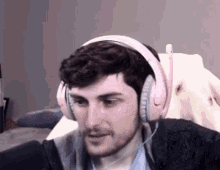 a man wearing a pair of pink headphones is sitting in front of a white dog .