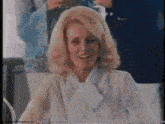 a woman in a white blouse and bow tie is smiling .