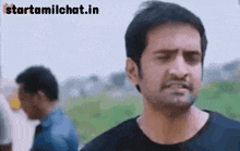 a man in a black shirt is making a funny face while another man stands in the background .