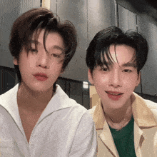 two young men are standing next to each other and one of them is wearing a green shirt