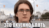 a man wearing glasses stands in front of a crowd of people with the words " это охуенно блять " written below him