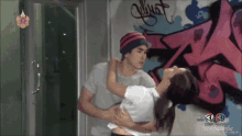 a man is holding a woman in front of a wall that has graffiti on it and the number 3 on it