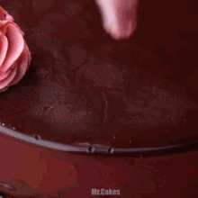 a chocolate cake is being decorated with pink frosting and the word mr.cakes is on the bottom