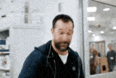 a man with a beard and a stethoscope around his neck walks through a hospital room