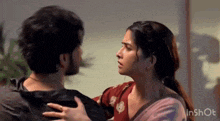 a man and a woman are hugging and looking at each other in a room .