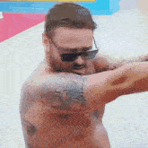 a shirtless man with a tattoo on his arm wearing sunglasses