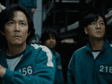 a man with the number 56 on his jacket stands next to a man with the number 218 on his jacket