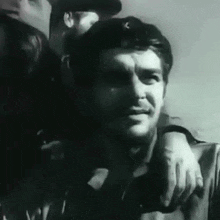 a black and white photo of a man with a beard standing next to a woman .