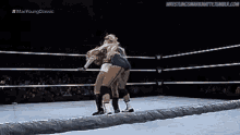two women are wrestling in a wrestling ring and one of them is wearing shorts