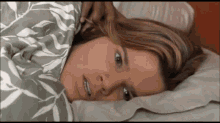 a woman is laying on a bed with a blanket on her head