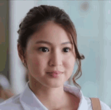 a close up of a woman 's face with a white shirt and brown purse .