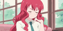 a girl with red hair is sitting on a couch with her eyes closed and her hand on her chin .