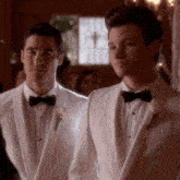 two men in white tuxedos with bow ties are standing next to each other