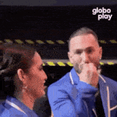 a man and a woman are sitting next to each other and the man is covering his mouth .