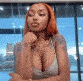 a woman with red hair and a tattoo on her arm is looking at the camera