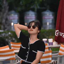 a woman wearing sunglasses stands in front of an umbrella that says ' cran ' on it