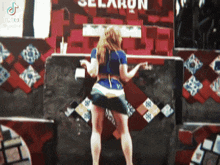 a woman standing in front of a sign that says selaron
