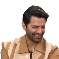 a man with a beard wearing a brown and white striped jacket is smiling