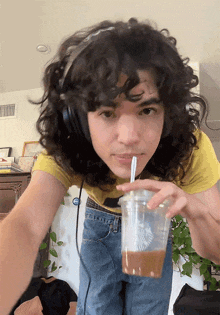 a young man wearing headphones drinking from a starbucks cup