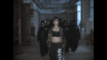 a woman in a leopard print jacket stands in a hallway surrounded by people wearing masks