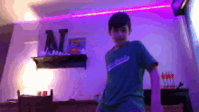 a boy wearing a green shirt with the word scouts on it is dancing in a room with purple lights