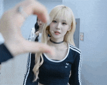 a woman making a heart shape with her hands in front of her