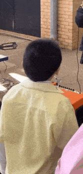 a boy in a yellow shirt is sitting in front of an orange amplifier