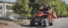 a man and a woman are riding a red atv