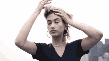a woman in a black shirt is holding her hair in her hands .