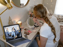 a woman is applying makeup in front of a laptop that says asus on it
