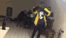 a man in a yellow and black jacket is standing in a room with other men .