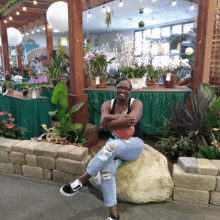 a woman is sitting on a rock in front of flowers