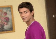 a man in a purple shirt is standing in front of a picture