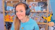 a woman wearing headphones is standing in front of a shelf with stuffed animals on it .