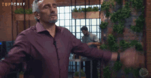 a man with his arms outstretched in front of a wall that says top chef on it