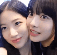 two girls are posing for a picture together and one of them is touching the other 's cheek .