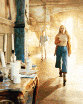 a man and a woman are walking down a hallway with candles on the table